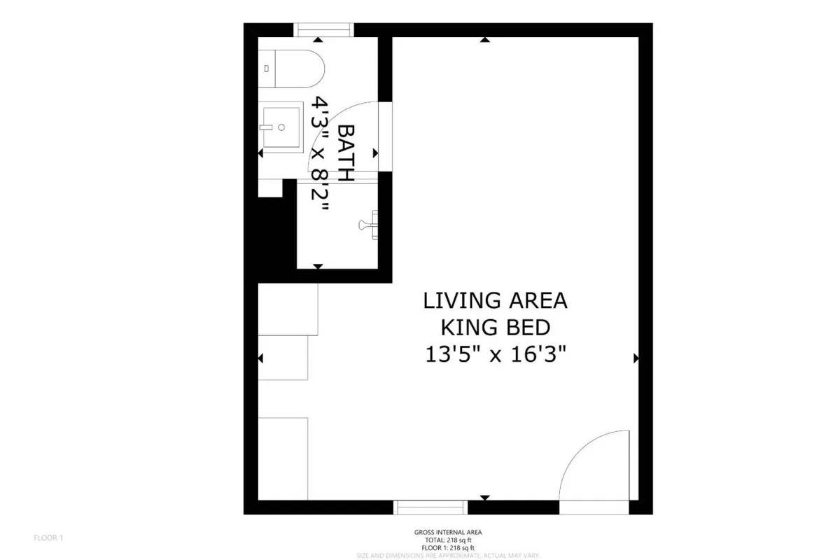 A cozy studio interior featuring a plush king-sized bed with soft bedding, a view into a contemporary bathroom area, and a comfortable living space. The décor displays soothing coastal colors, creating a tranquil and inviting atmosphere.