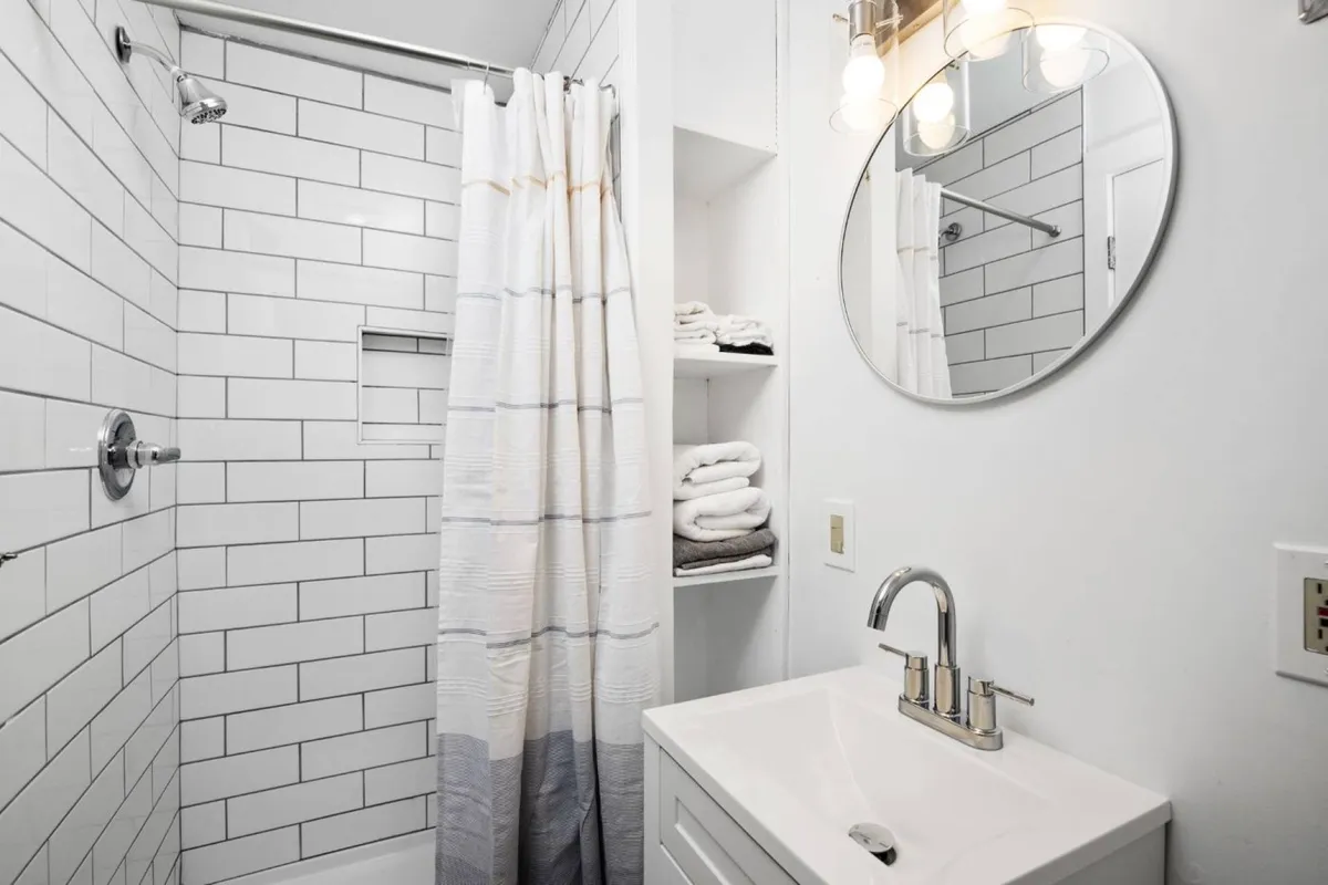 A modern bathroom featuring a glass-enclosed shower, a mirrored vanity with ample storage, and neatly arranged towels, all set in a serene, spa-like environment.